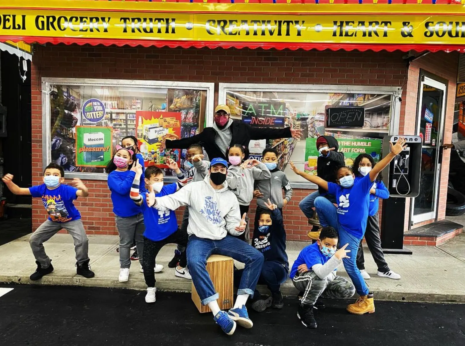 Volunteers in blue shirts in front of the Deli Grocery storefront