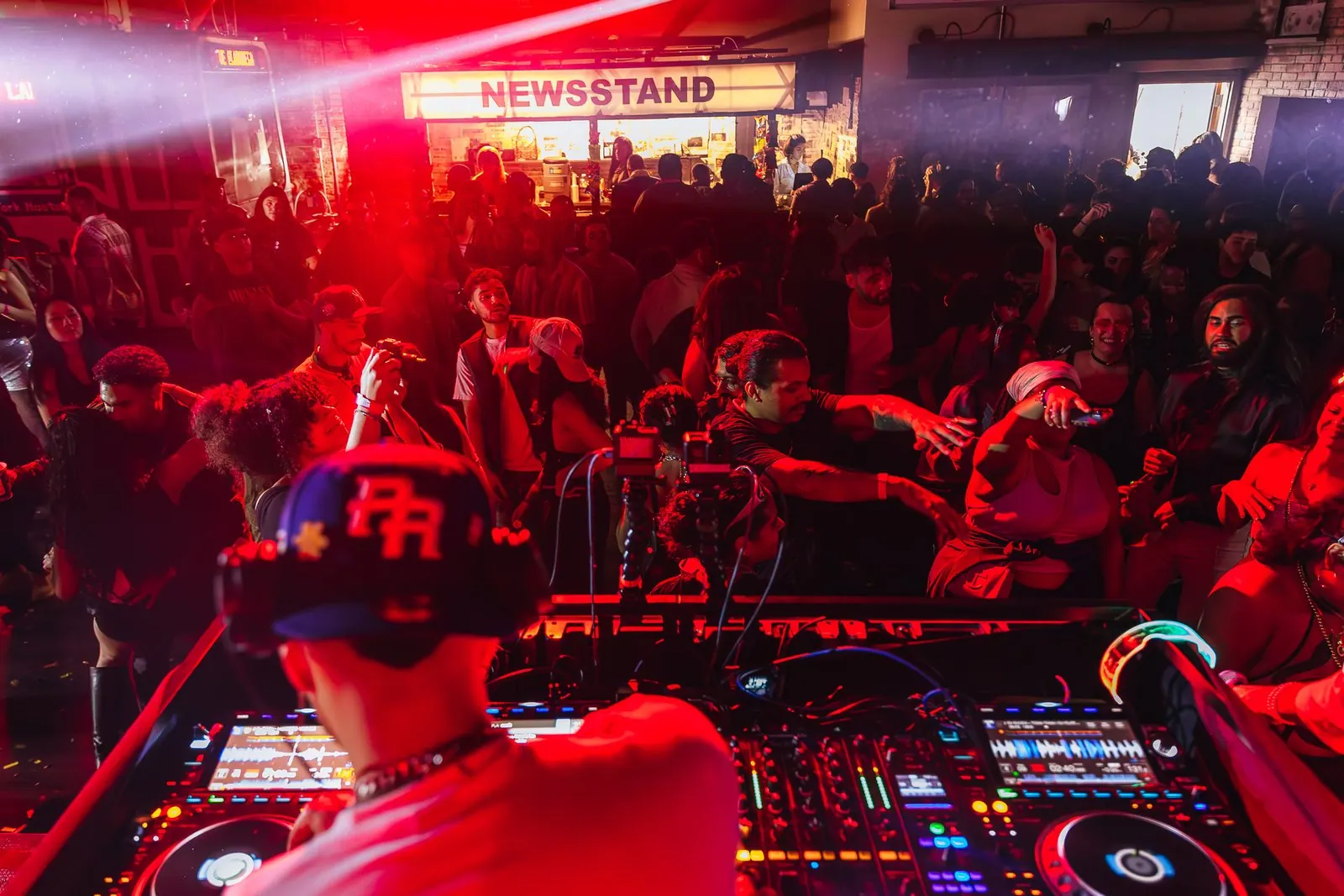 Packed New Year's party under red lights with the DJ booth up front