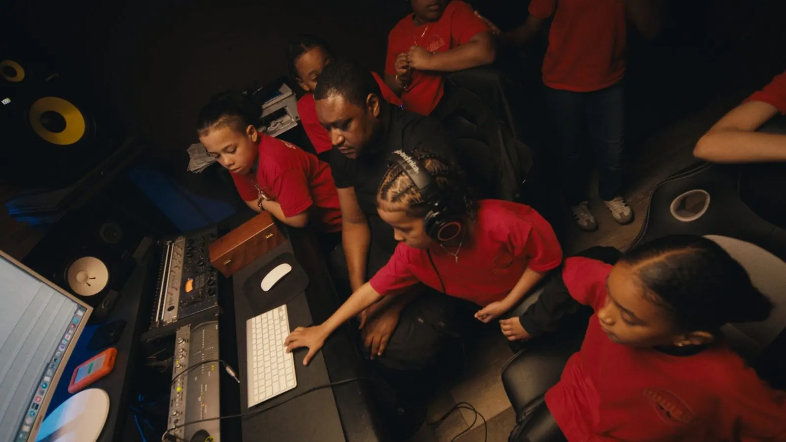 Students in red La Bodega T-shirts gathered around a mixing console