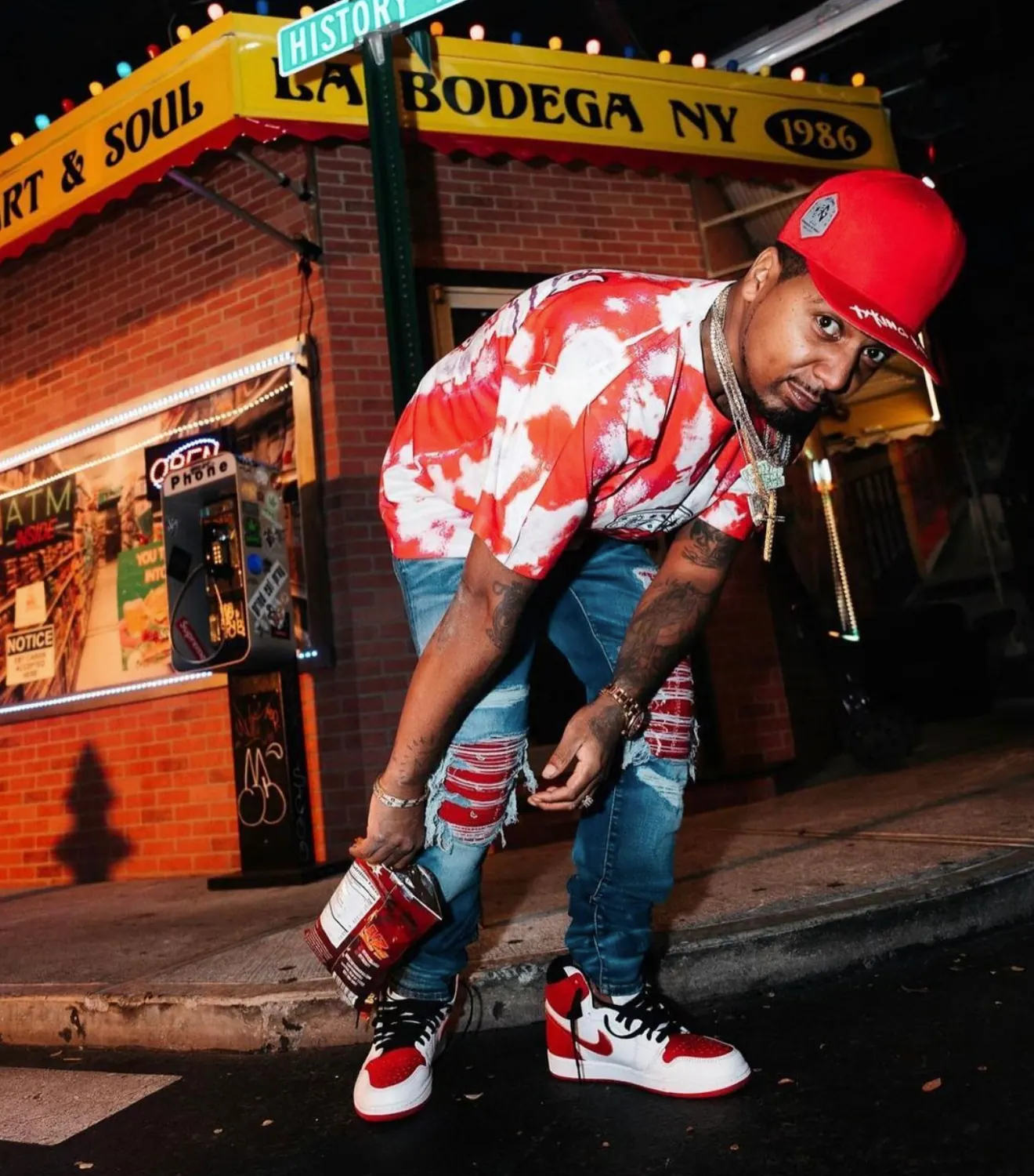 Artist crouching under the La Bodega NY corner-store awning