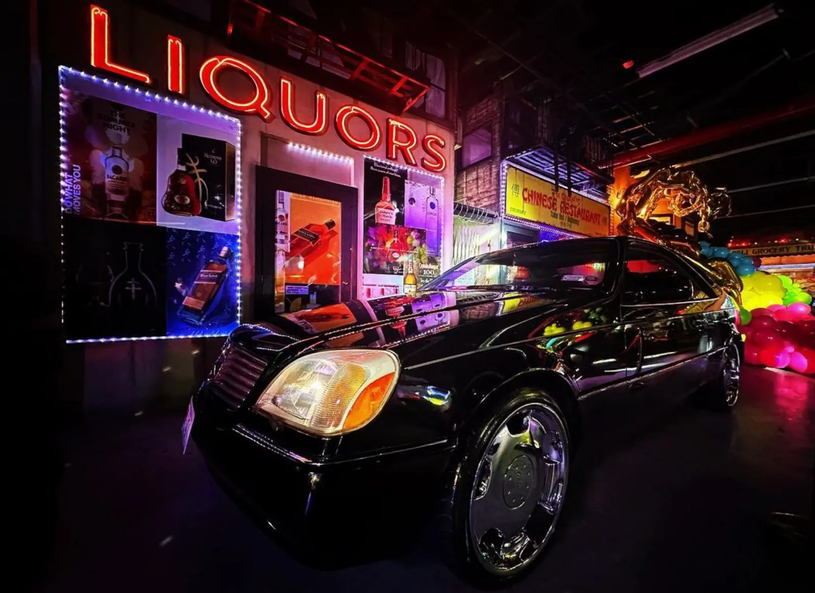 Black Mercedes parked in front of the storefronts at night