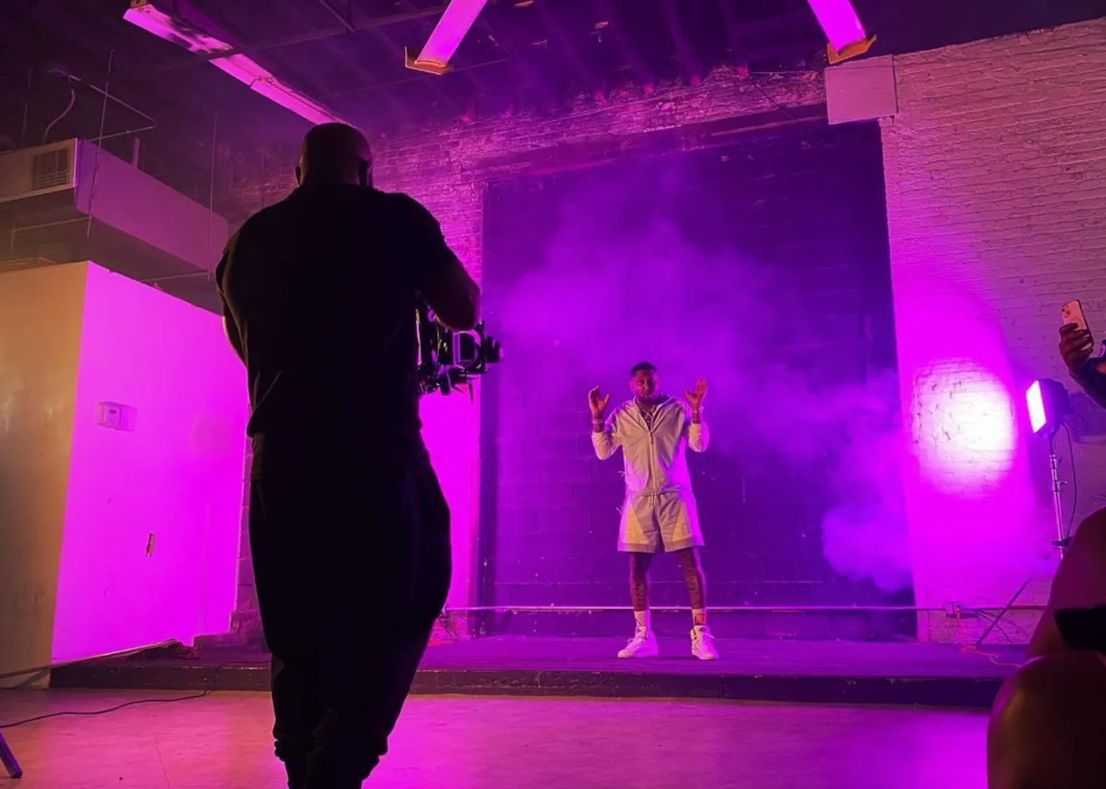 Music video shoot with a performer on a smoky, purple-lit stage