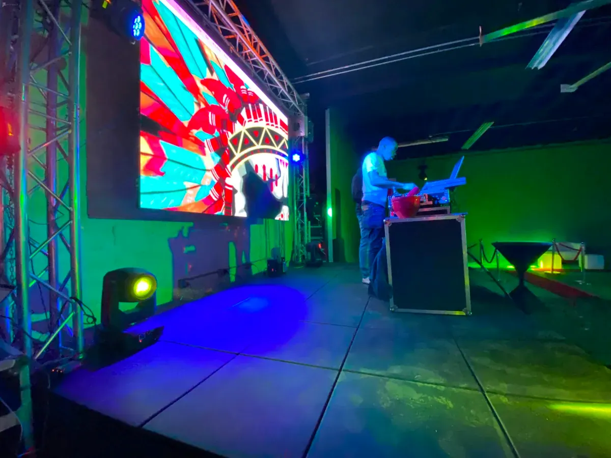 Event setup with an LED video wall, green light and a DJ booth