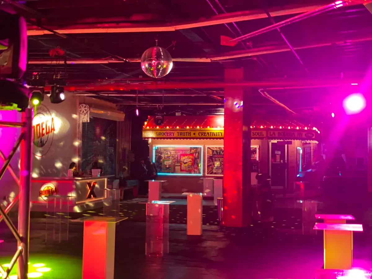 The venue lit in pink and red neon with storefront facades
